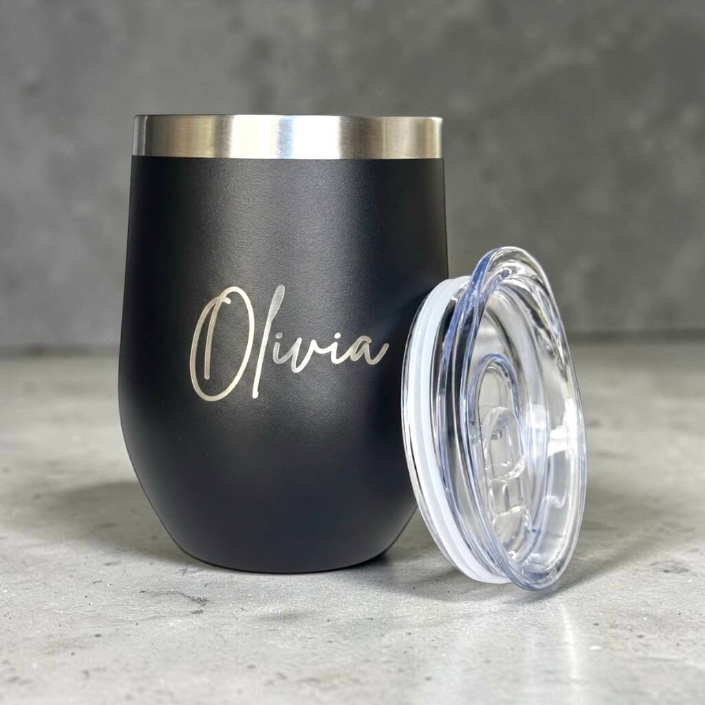 Personalised black coffee cup engraved with Olivia beside clear lid