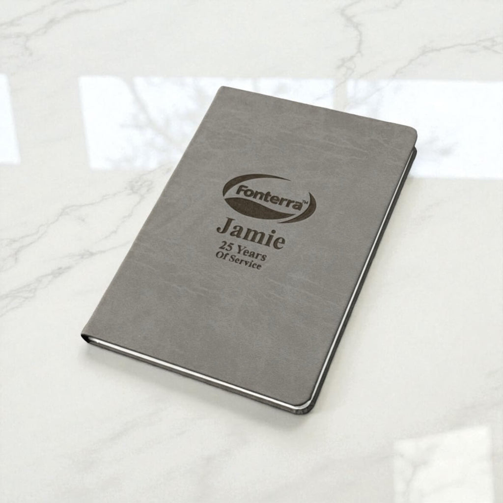 Personalised company logo journal on marble surface, engraved with name and years of service, an elegant business gift for NZ employees.