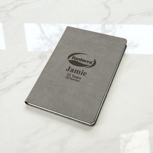 Personalised company logo journal on marble surface, engraved with name and years of service, an elegant business gift for NZ employees.