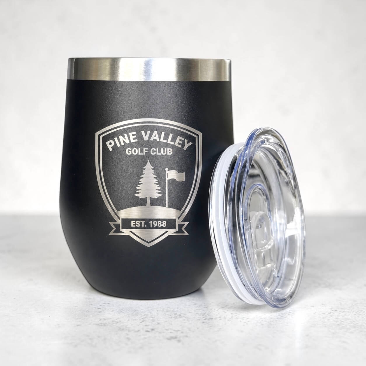 Personalised corporate coffee cup with clear lid beside engraved tumbler