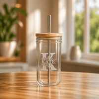 Personalised engraved glass jar tumbler with bamboo lid and metal straw, featuring floral monogram letter K and name Kate, sitting on a wooden table