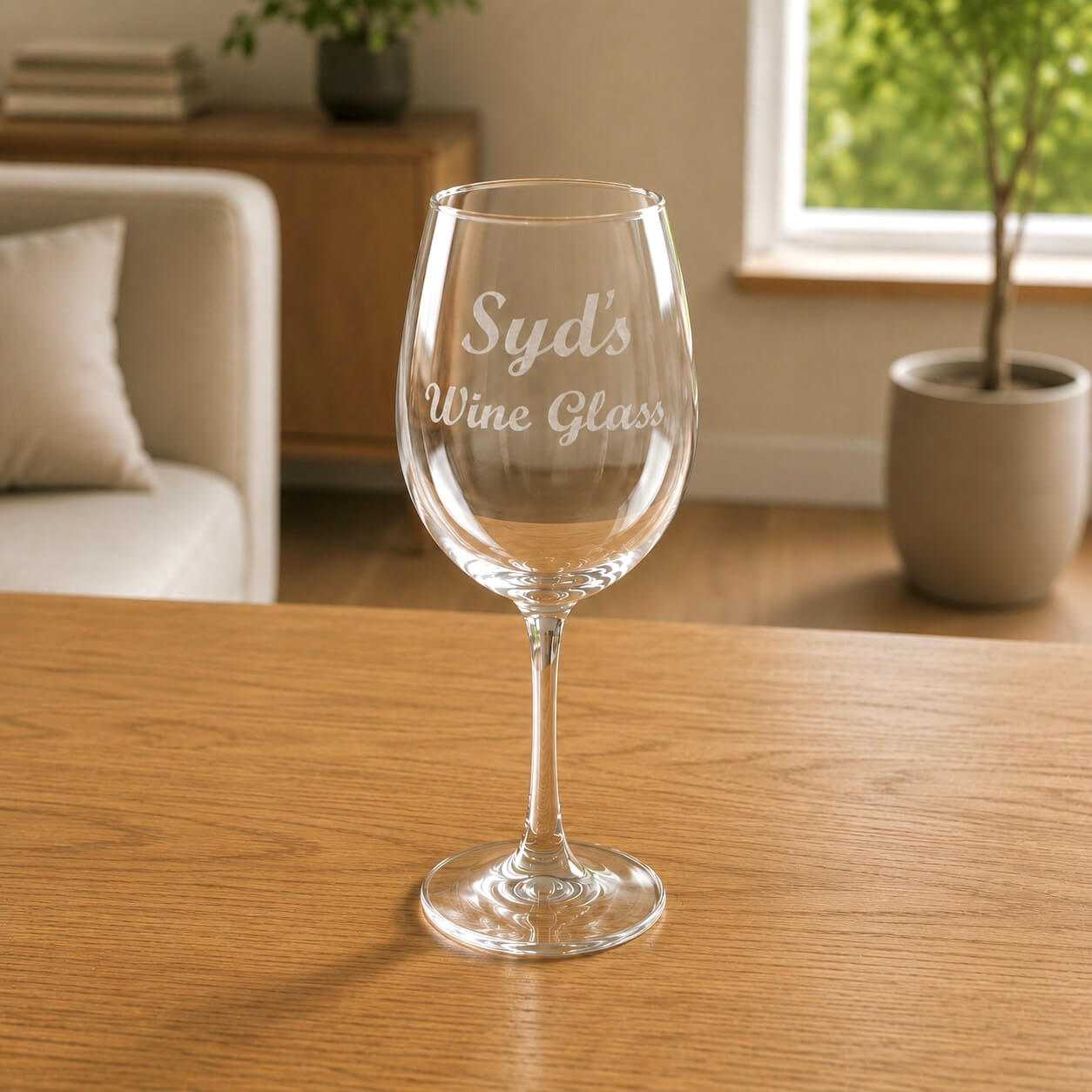 Personalised engraved wine glass with a custom name as a unique gift idea, displayed on a wooden table in a bright modern interior