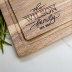 Personalised family name chopping board engraved with The Wilson Family Est. 2024, custom acacia wood gift for new home or housewarming.