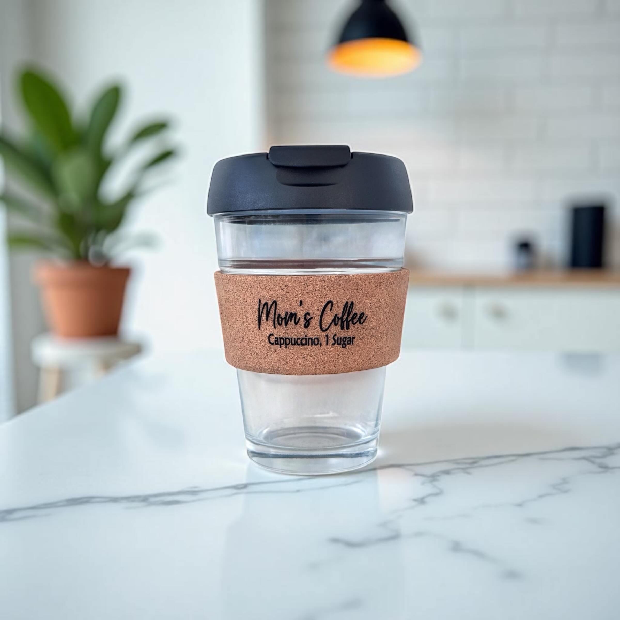 Personalised glass coffee cup engraved “Mom’s Coffee, Cappuccino 1 Sugar” on white desk