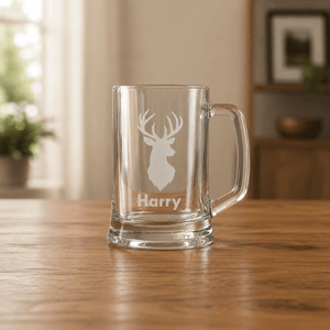 Personalised glass mug with deer head engraving and 'Harry' text on a wooden table.