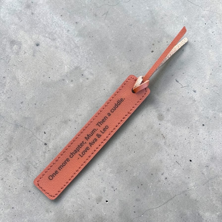 Personalised leather bookmark engraved with custom quote on a concrete surface