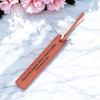 Personalised leatherette bookmark engraved with custom quote on marble surface.
