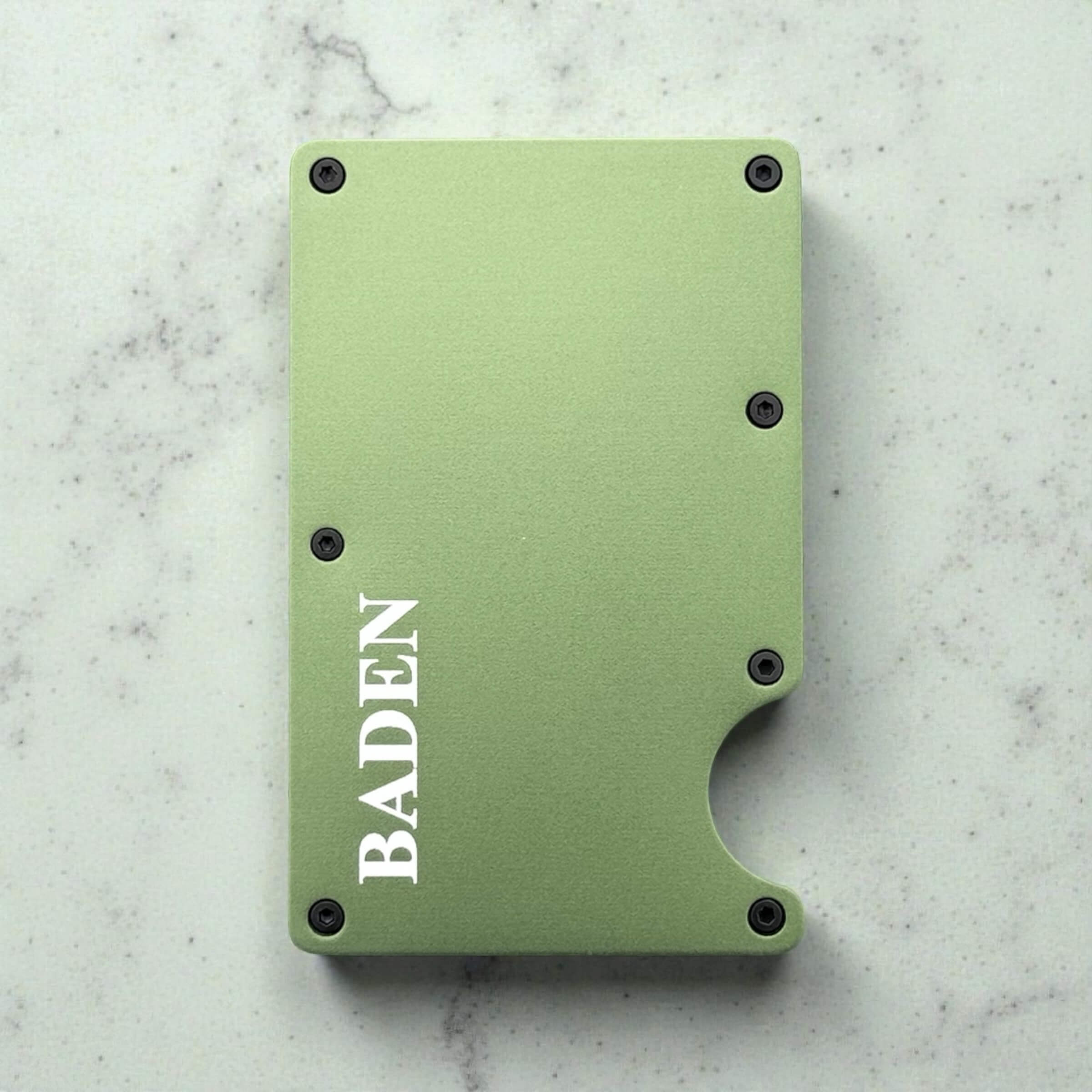 Personalised metal green cardholder with 'BADEN' branding on a marble surface