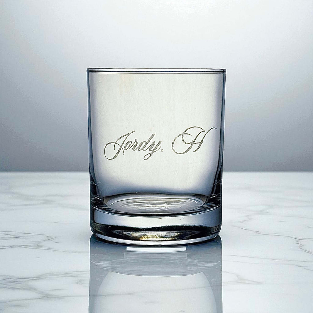 Personalised scotch glass engraved with a name, shown on marble surface