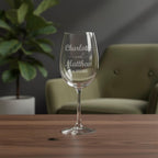 Personalised wedding wine glass engraved with Charlotte and Matthew names and date on wooden table