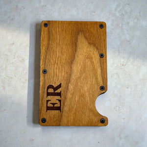 Personalised wooden card holder with engraved initials shown from the front on a light surface