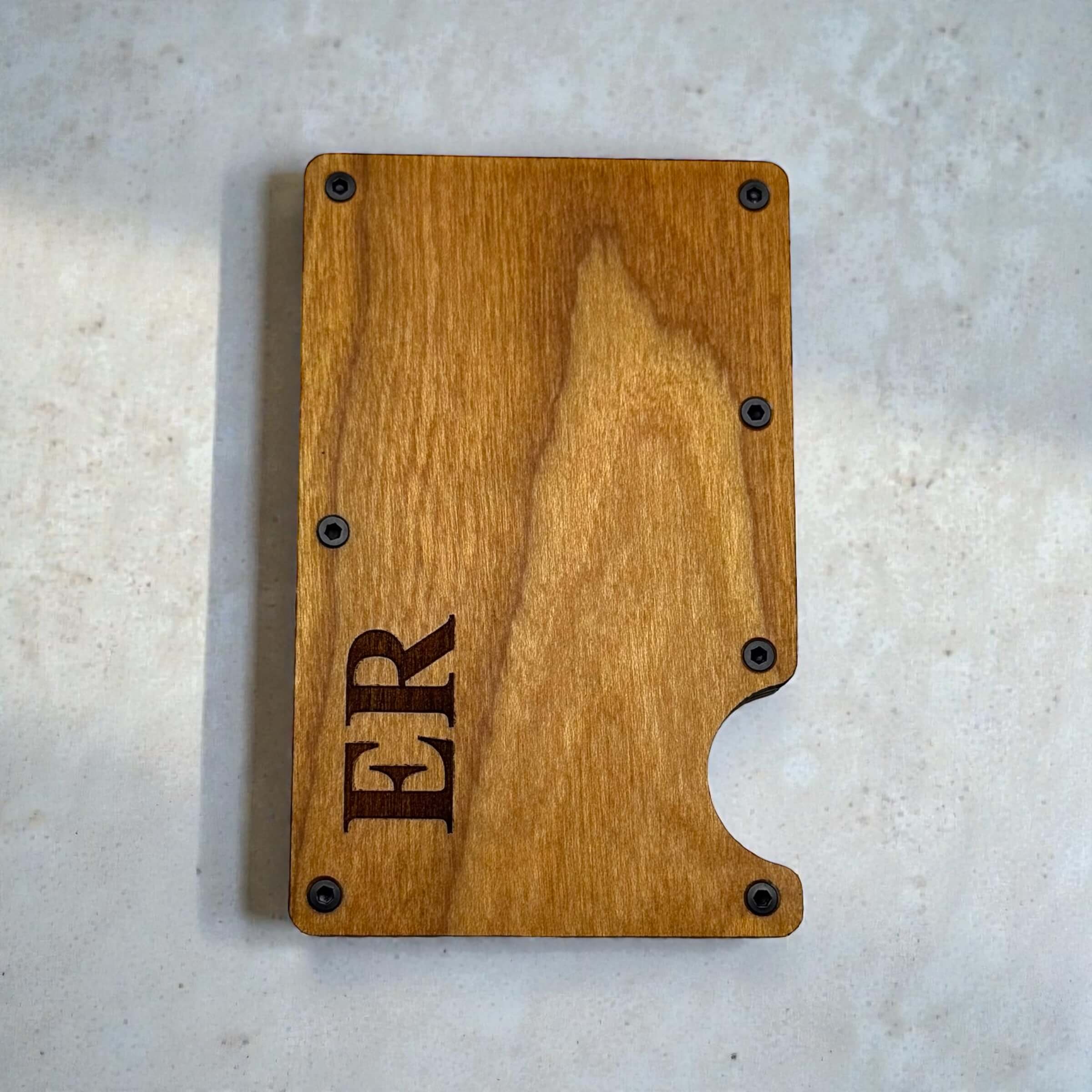 Personalised wooden card holder with engraved initials shown from the front on a light surface