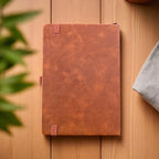 Rear cover of the tan PU leather planner with visible texture, band accents and clean stitching on a timber backdrop