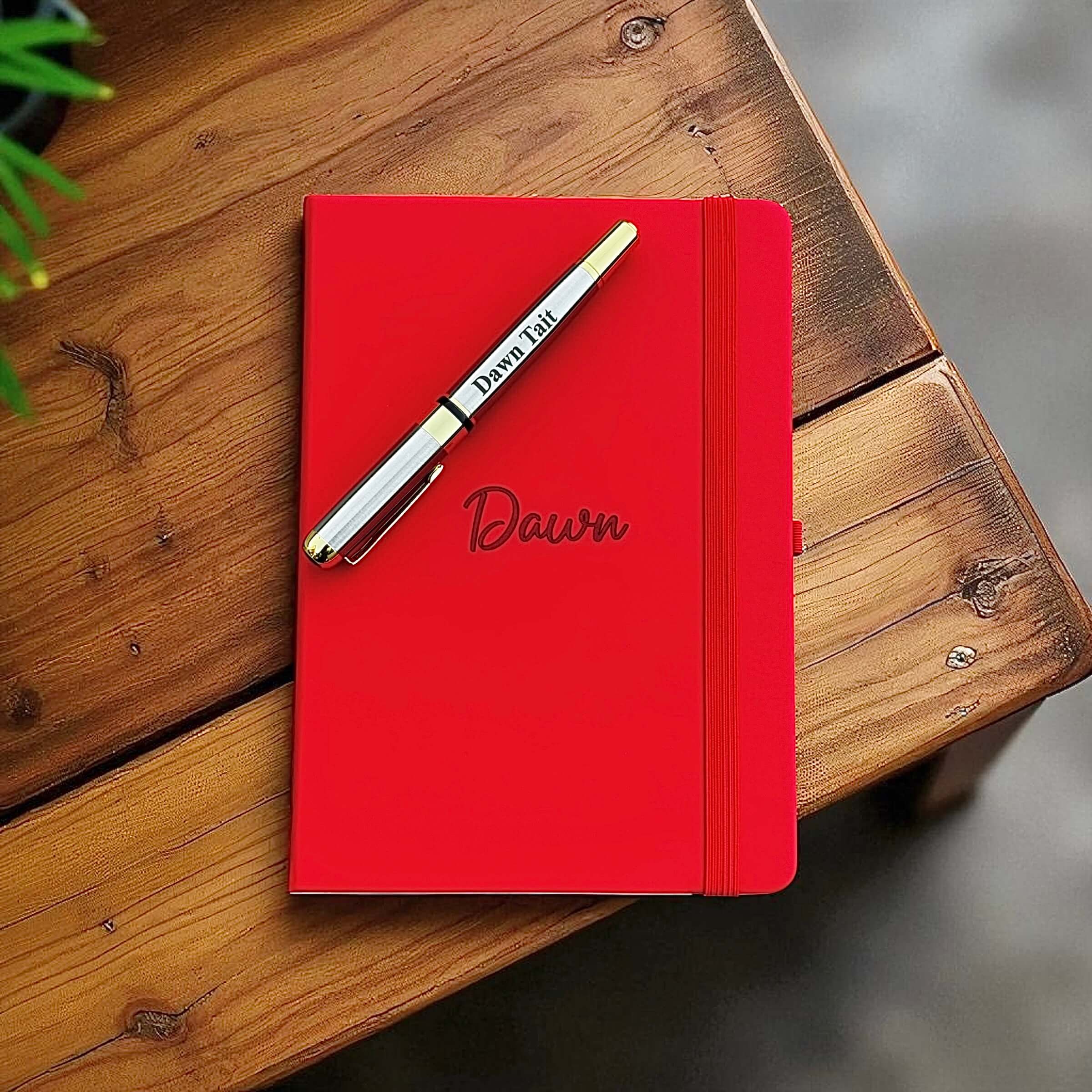 Red personalised A5 leather journal with engraved name and matching pen on a wooden desk