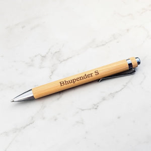 Retractable bamboo ballpoint pen with personalised message on a marble surface