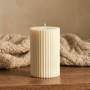 Scented soy candle displayed on a wooden surface with a beige knitted blanket in the background