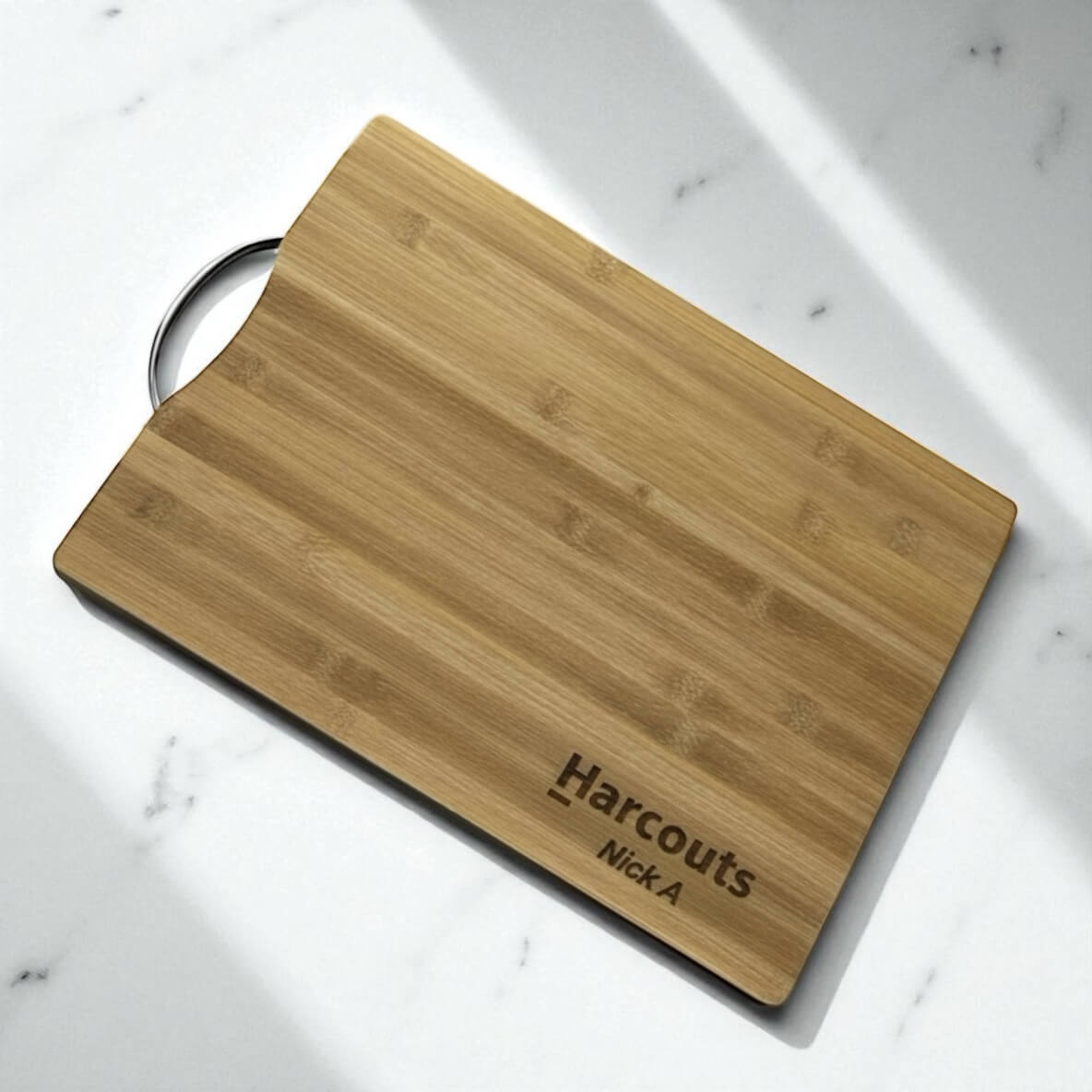 Side angle of engraved bamboo chopping board with stainless steel handle, personalised for corporate gifting.