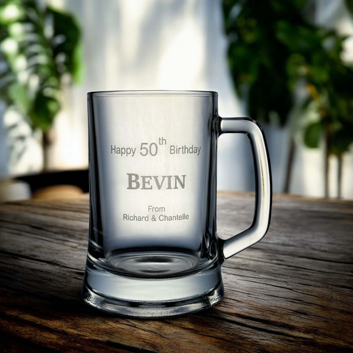 Side angle of engraved beer mug showing full name and birth year against a wooden surface.