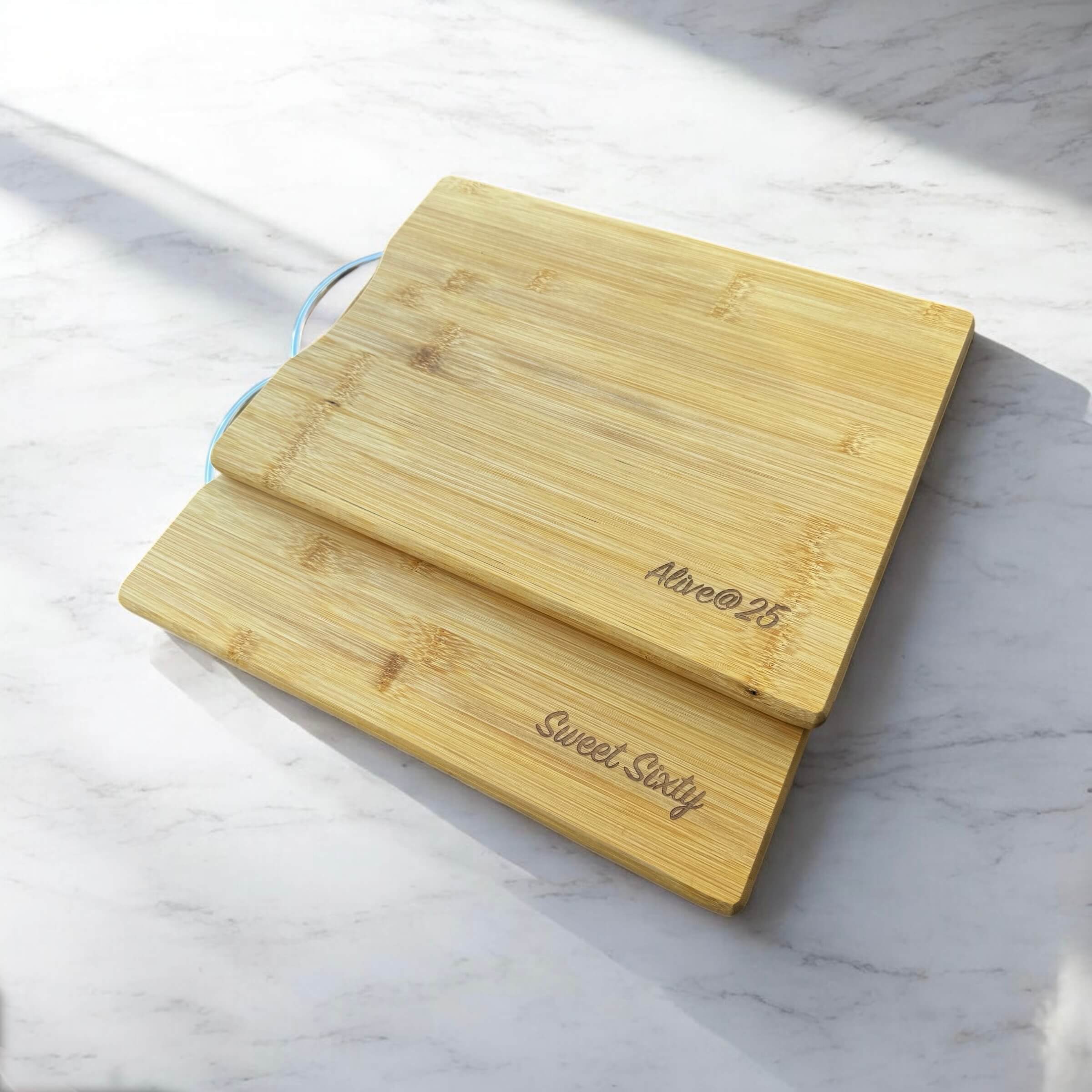 Side angle of personalised bamboo chopping board stacked on another engraved bamboo cutting board.