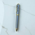 Silver and gold pen with 'Vertec' branding on a marble surface