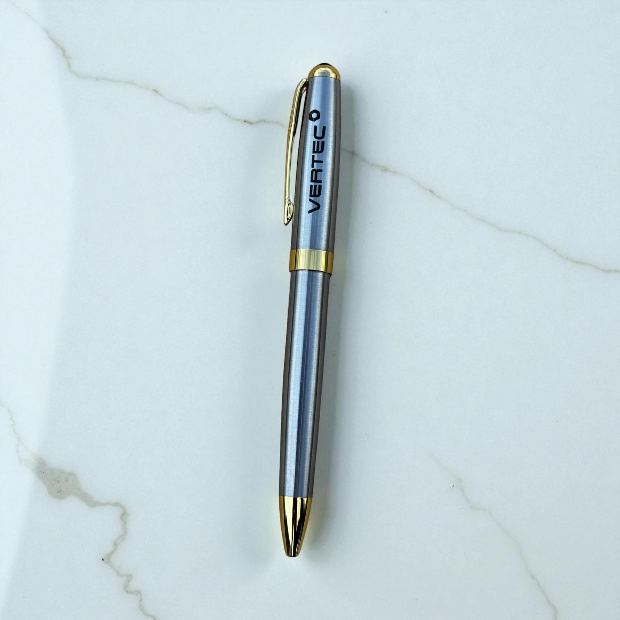 Silver and gold pen with 'Vertec' branding on a marble surface