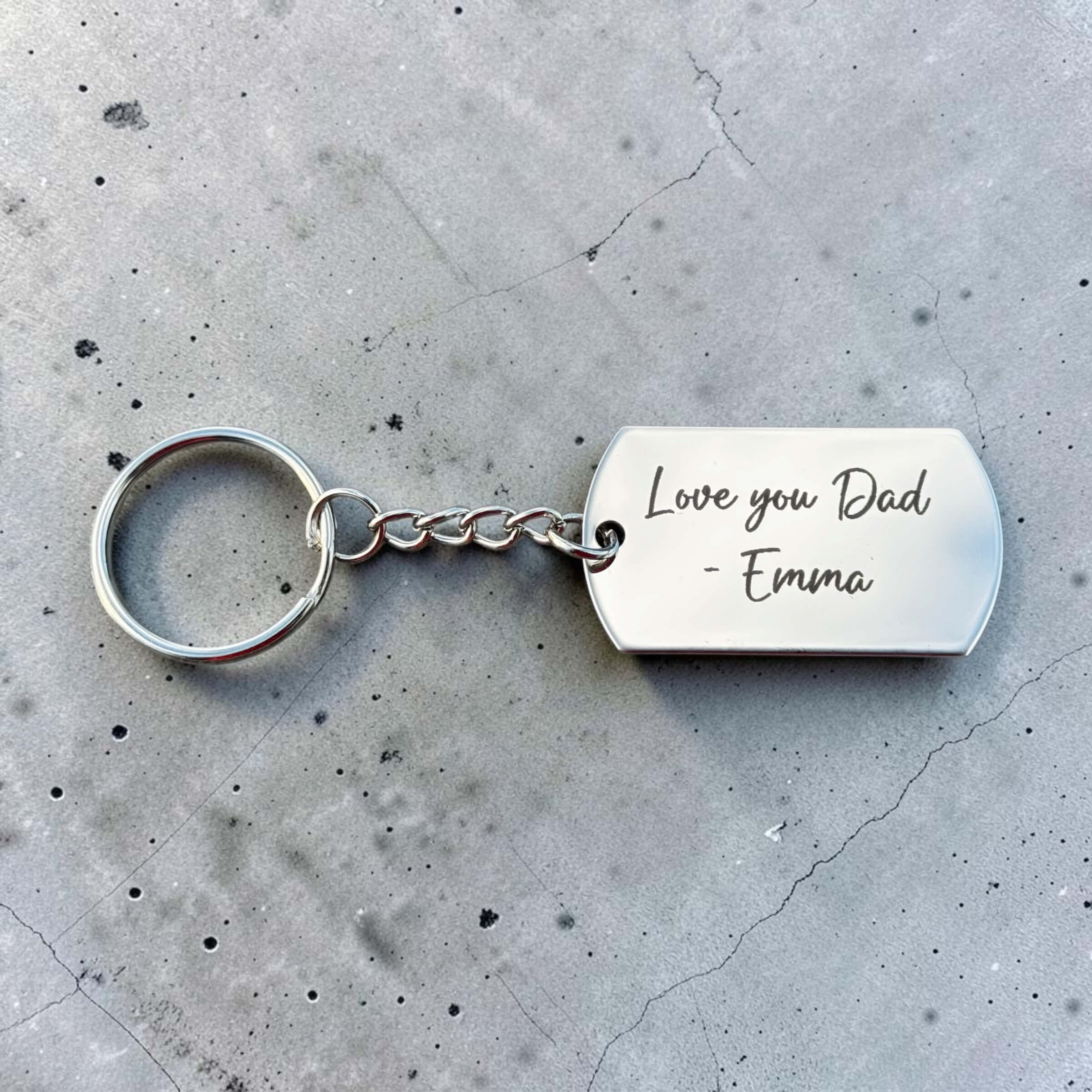 Silver personalised keyring for Dad engraved with Love you Dad - Emma on grey concrete