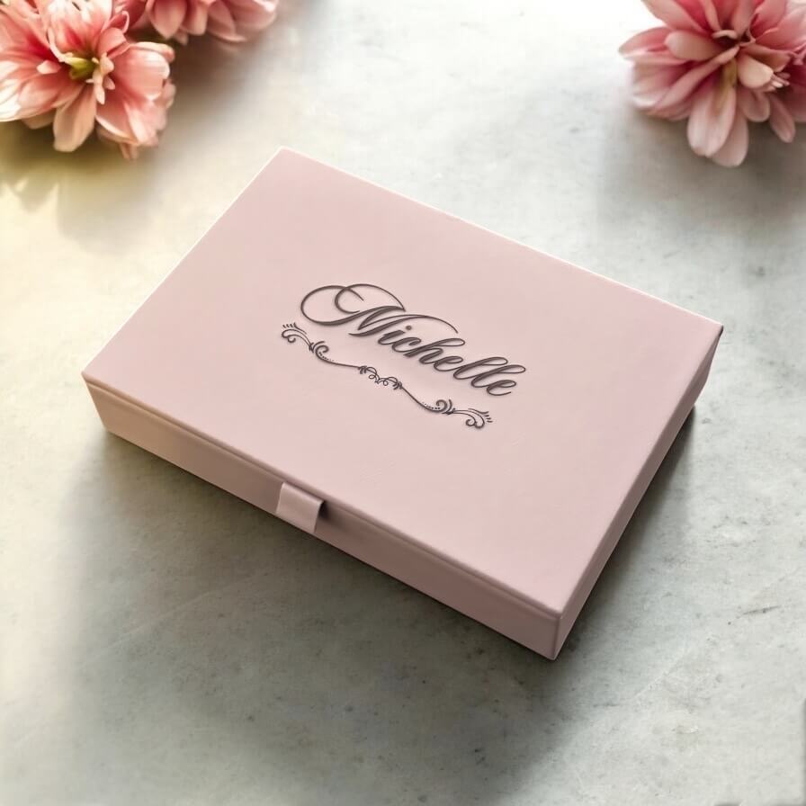 Taupe engraved jewellery box with personalised name displayed on marble surface in natural light.
