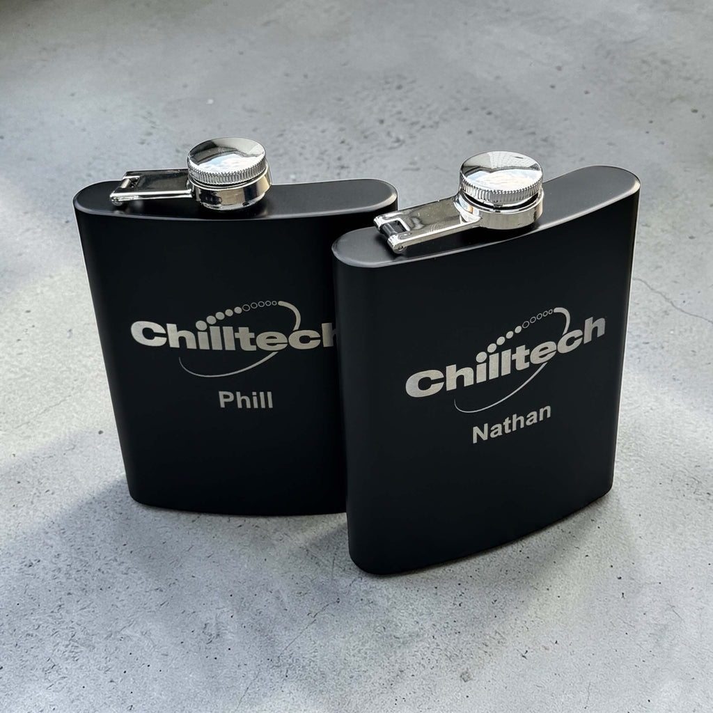 Two custom engraved black stainless steel hip flasks with corporate logo and personalised names, branded bulk corporate gifts