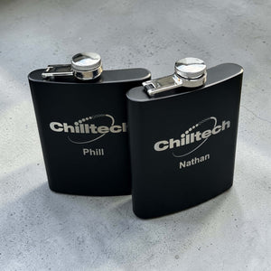 Two custom engraved black stainless steel hip flasks with corporate logo and personalised names, branded bulk corporate gifts