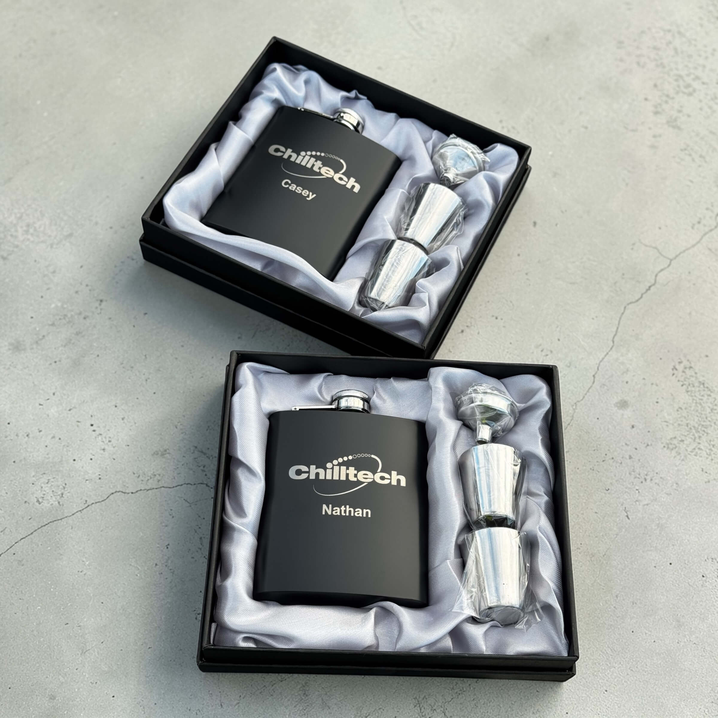 Two personalised corporate hip flask gift sets in black presentation boxes with shot glasses, custom engraved branded staff gifts