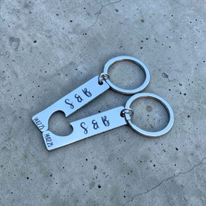 Two silver keychains with 'S & B' engraving on a concrete surface