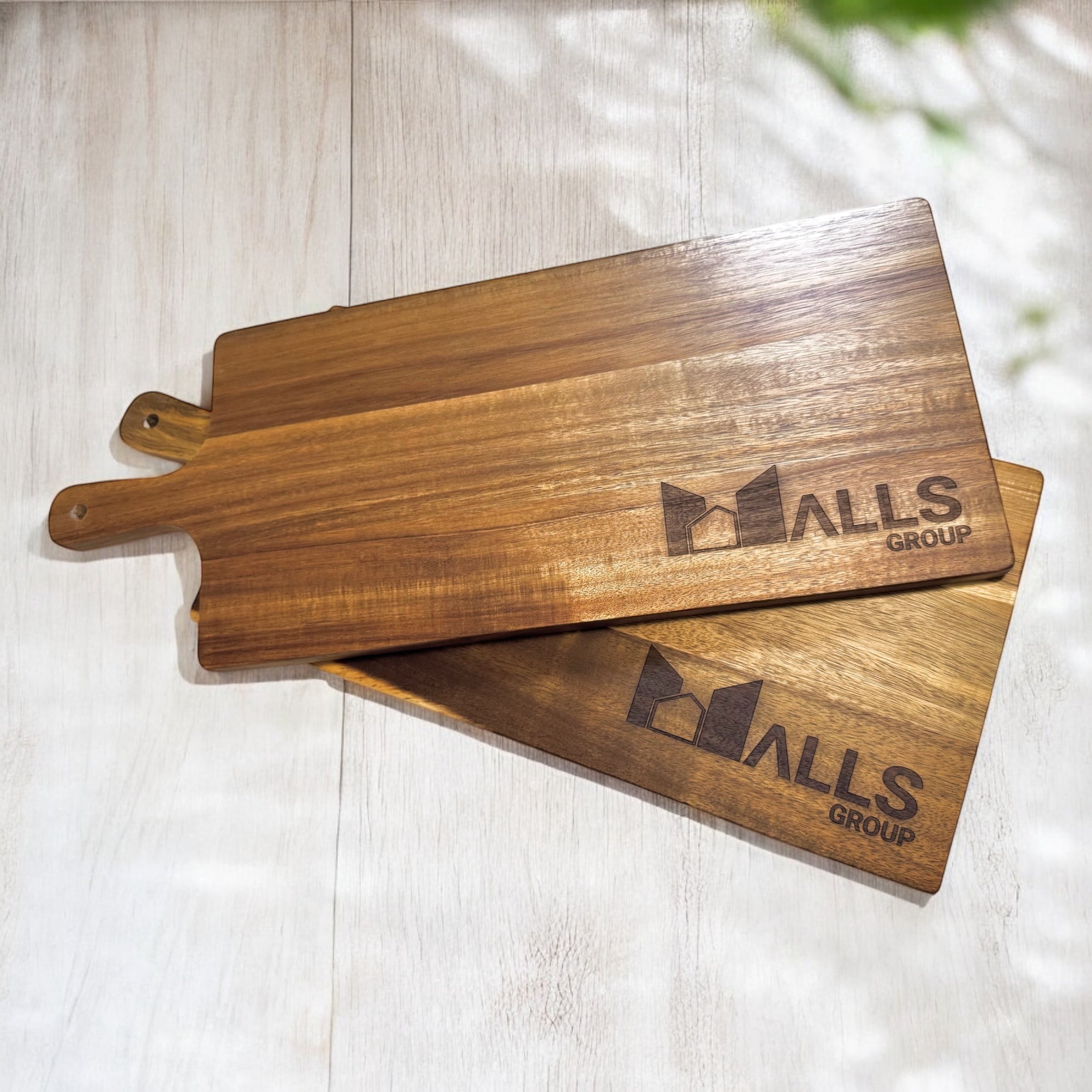 Two stacked engraved acacia serving boards showing grain detail and branding