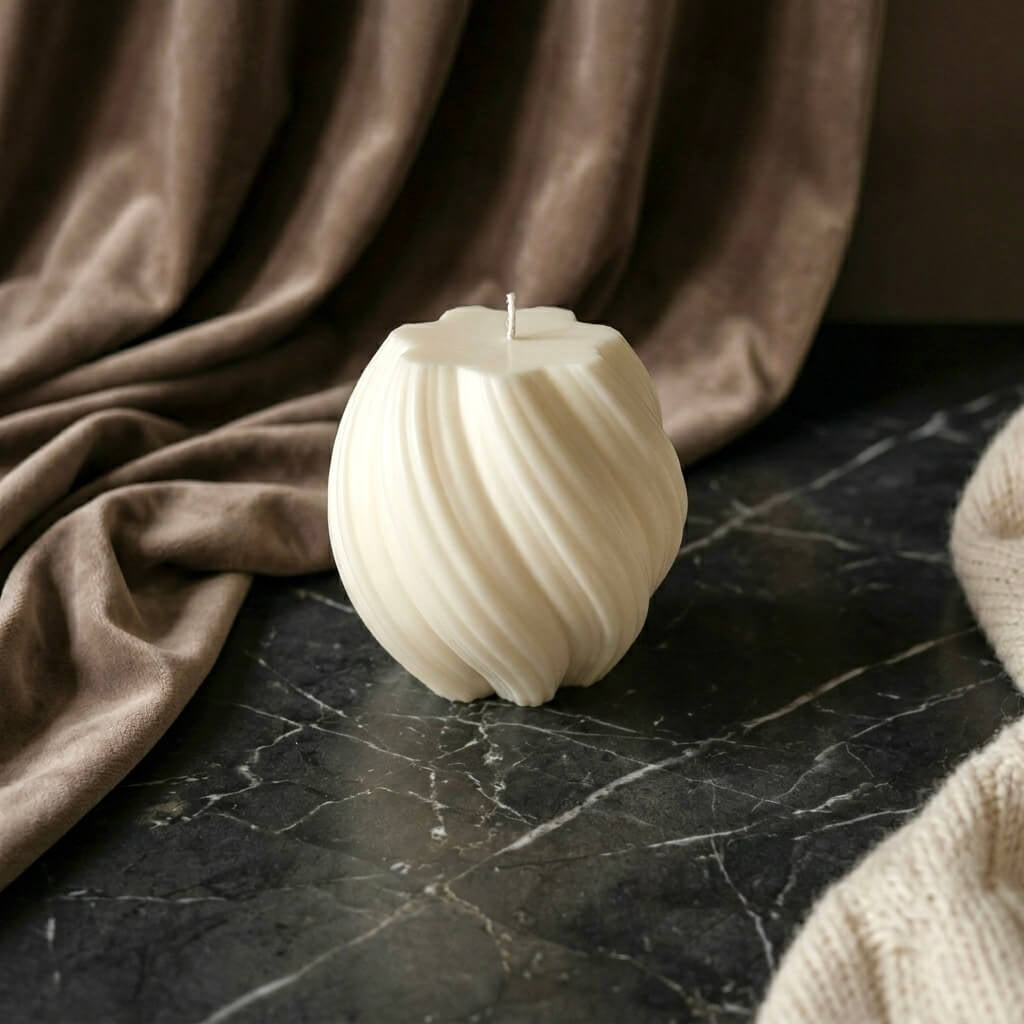 Unlit hand-poured ivory twisted sphere scented soy candle on dark marble, available in multiple colours and scents