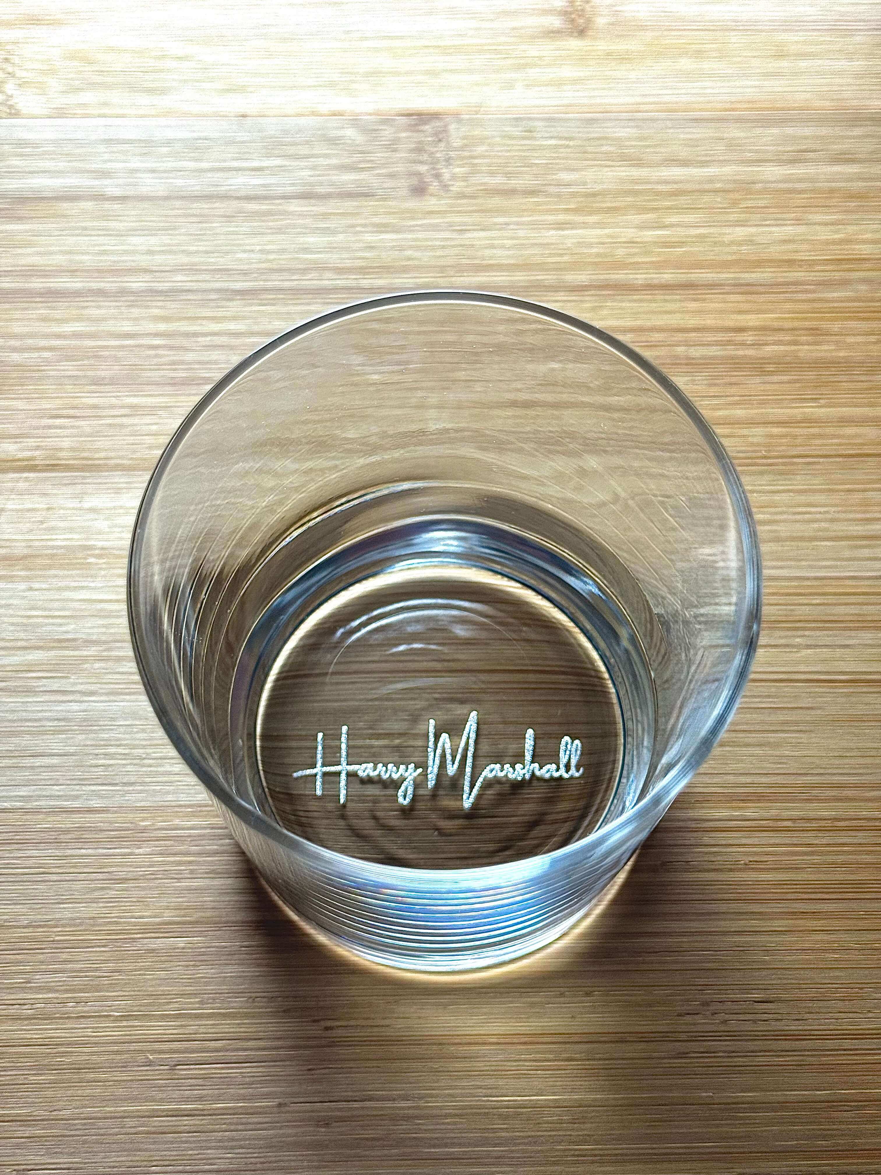 Whiskey glass placed on wooden surface personalised with name.
