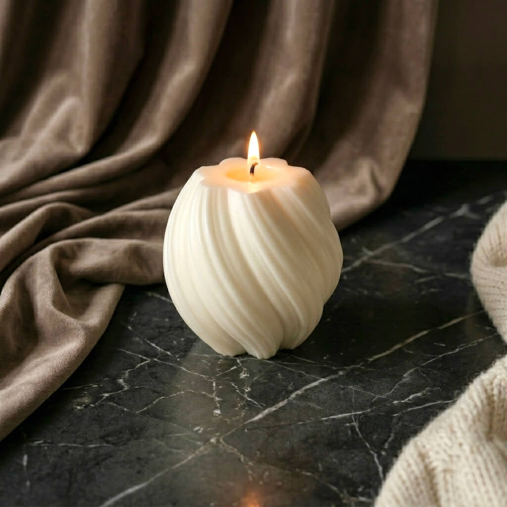 White textured scented soy candle burning on a dark marble surface with brown fabric in the background