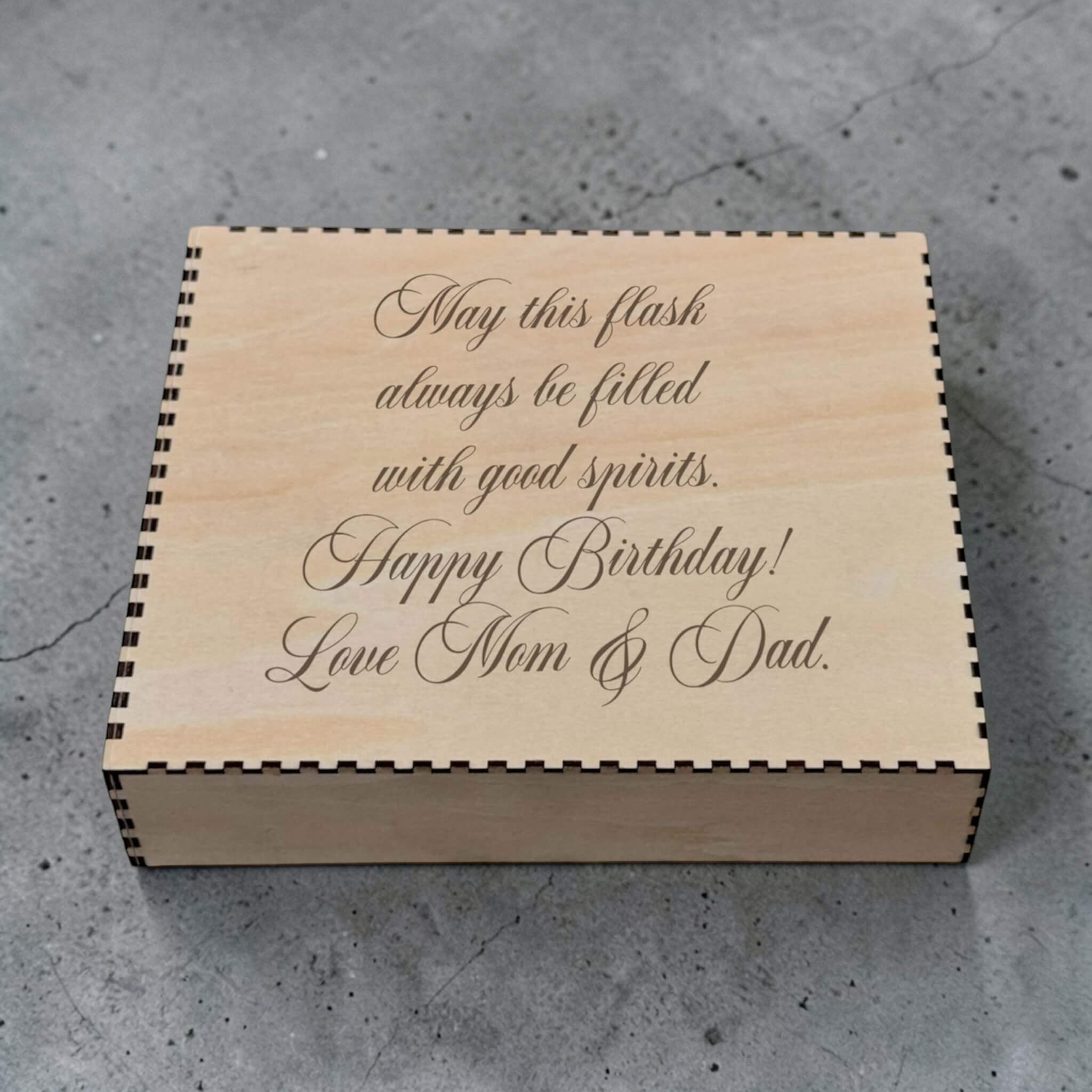 Wooden box with engraved birthday message from Mom & Dad on a concrete surface