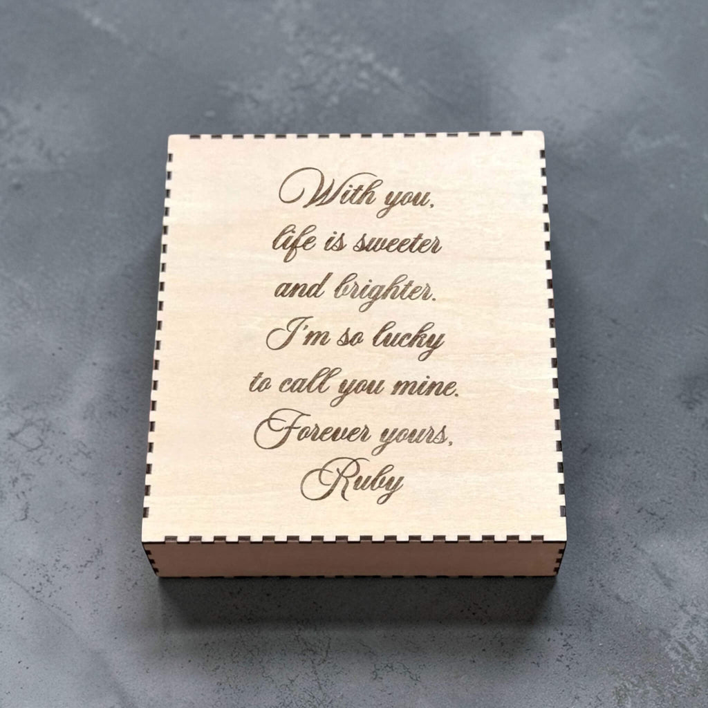 Wooden box with engraved romantic message on a gray surface
