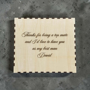 Wooden box with engraved with personalised text on a gray surface