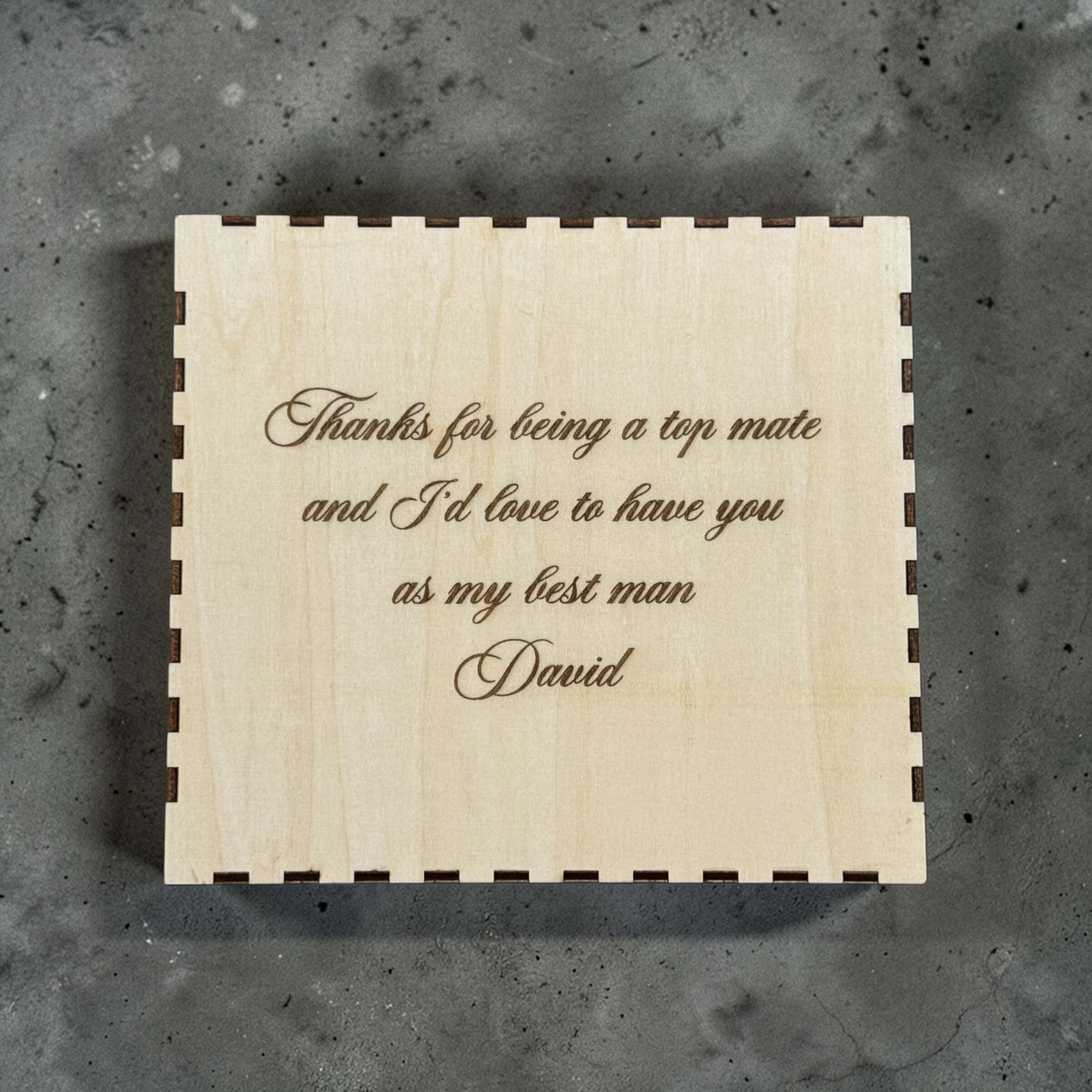 Wooden box with engraved with personalised text on a gray surface