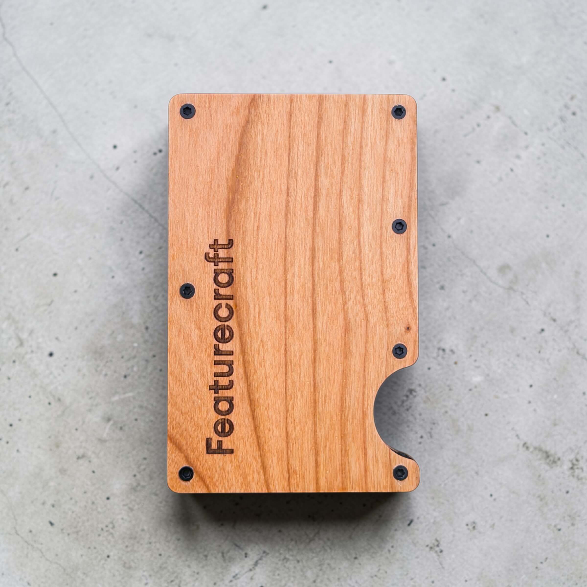 Wooden corporate logo and name engraved card holder displayed flat on a concrete background
