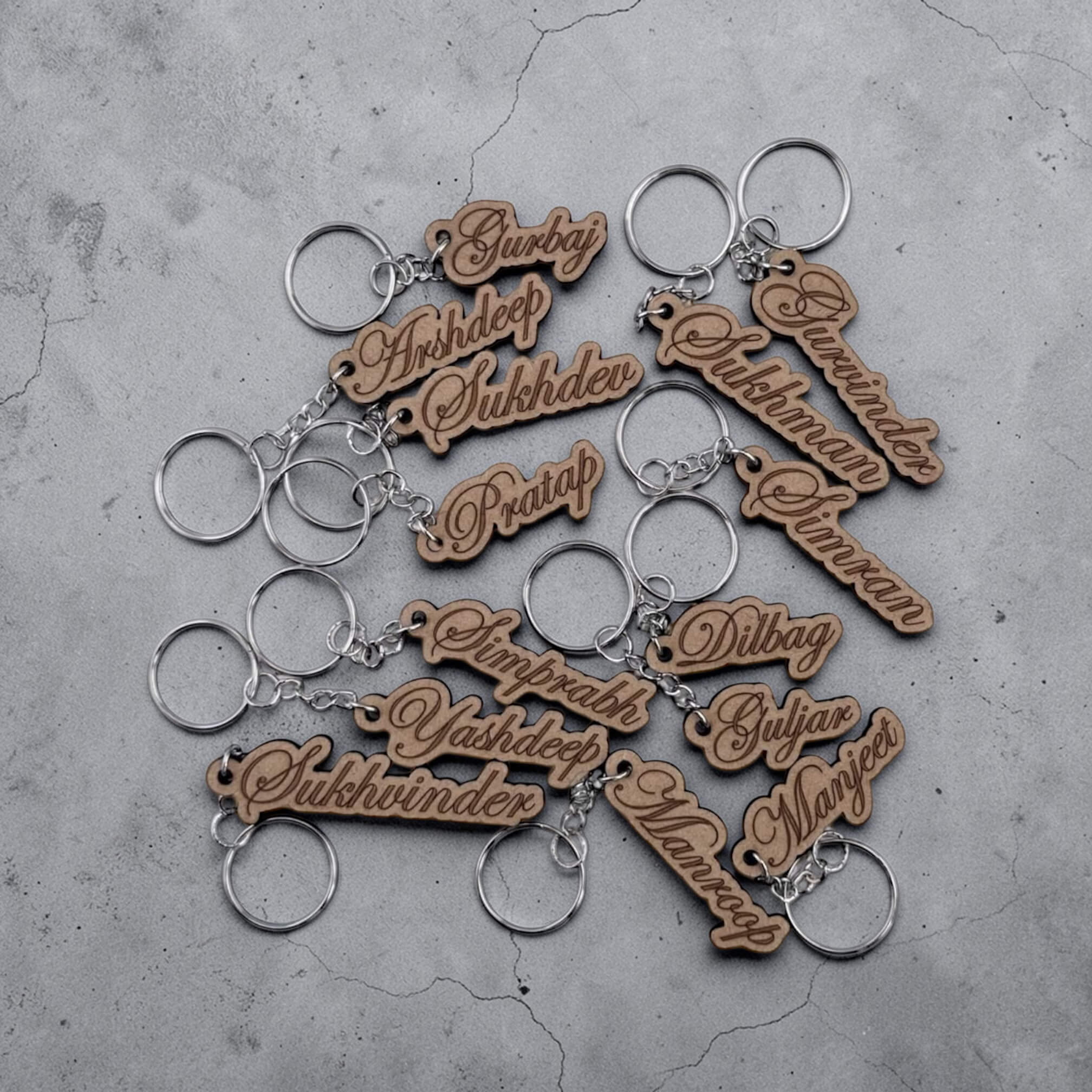 Wooden keychains with engraved names on a concrete surface