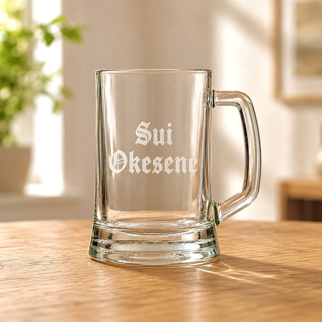 Clear beer mug with engraved Sui Okesene name in Old English font on wooden table
