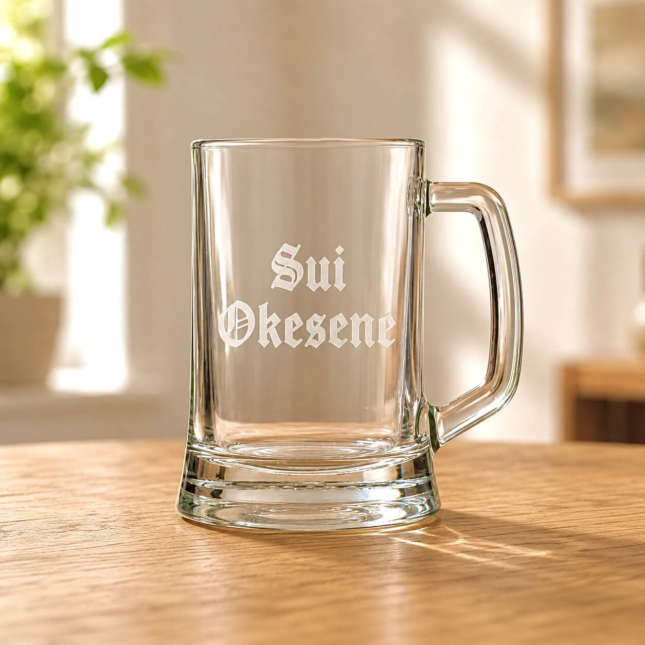 Clear beer mug with engraved Sui Okesene name in Old English font on wooden table