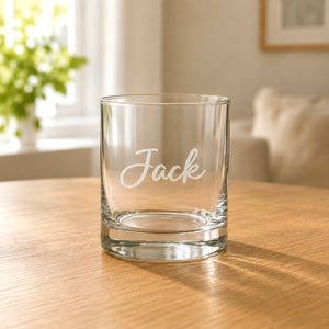 Clear scotch glass with engraved Jack name on wooden table in warm home setting