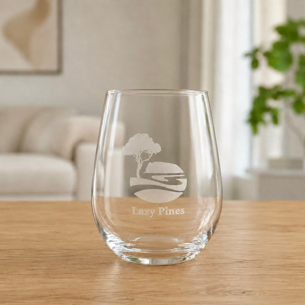 Clear stemless wine glass with engraved Lazy Pines logo on wooden table