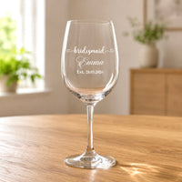 Clear wine glass with engraved bridesmaid Emma name and Est 28.03.2026 on wooden table