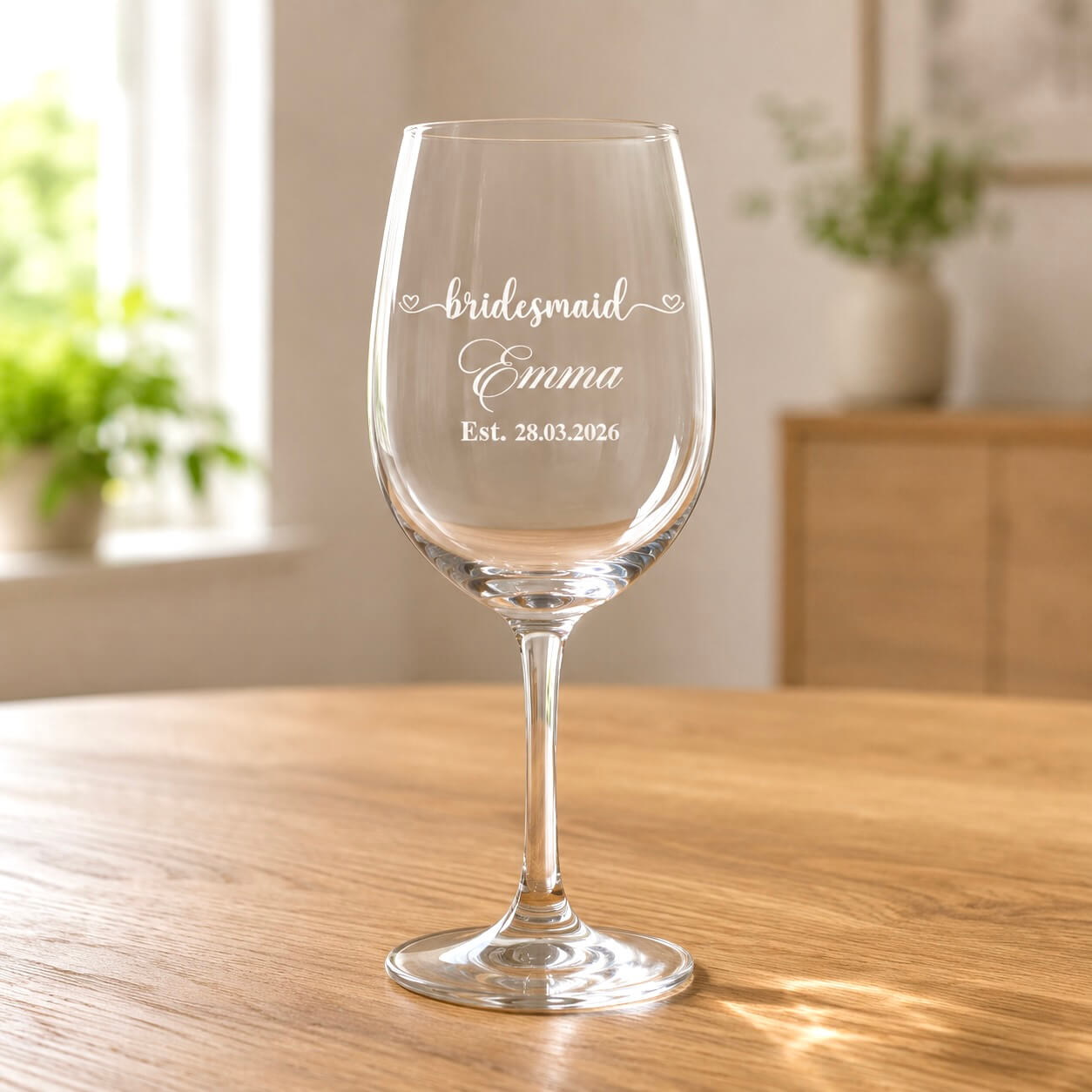 Clear wine glass with engraved bridesmaid Emma name and Est 28.03.2026 on wooden table
