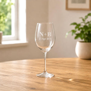 Engraved wine glass with couple initials and wedding date on wooden table