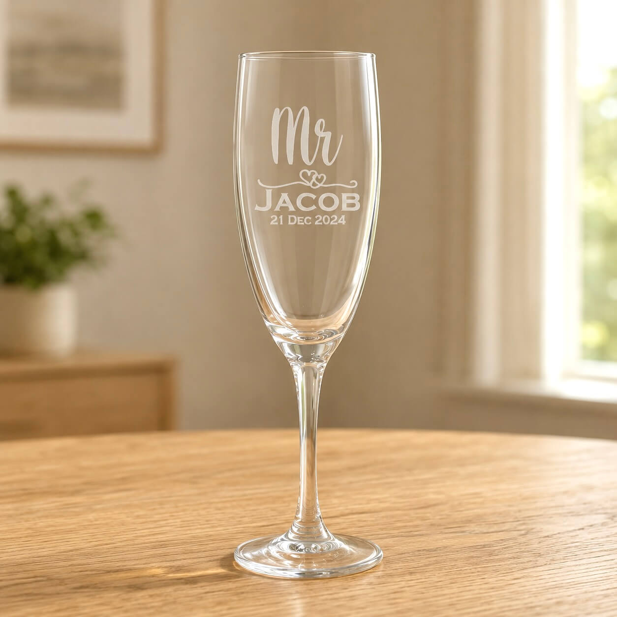 Clear glass Mr champagne flute with etched Jacob name and 21 Dec 2024 date on wooden table