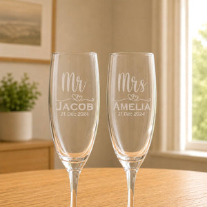 Close-up of personalised champagne flutes with frosted Mr and Mrs names, hearts and wedding date